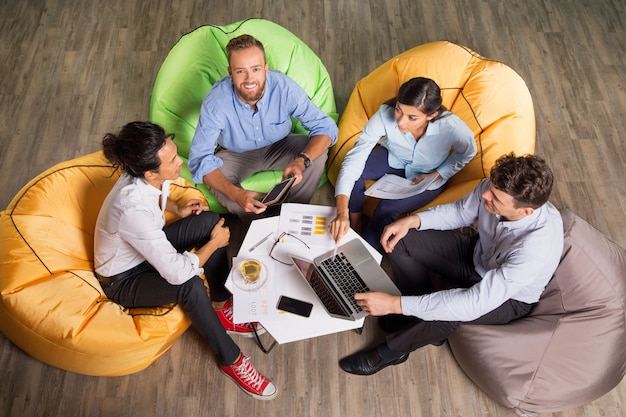 Free photo four young colleagues working on beanbag chairs