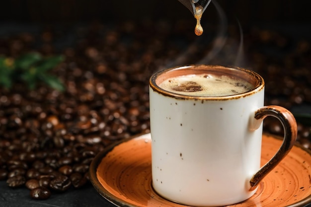 Fragrant espresso on a black table a drop of coffee from a  pot falls into a cup