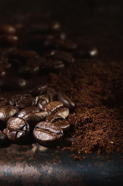 Fragrant freshly roasted coffee beans and ground coffee are scattered on a metal tray Closeup selective focus vertical frame