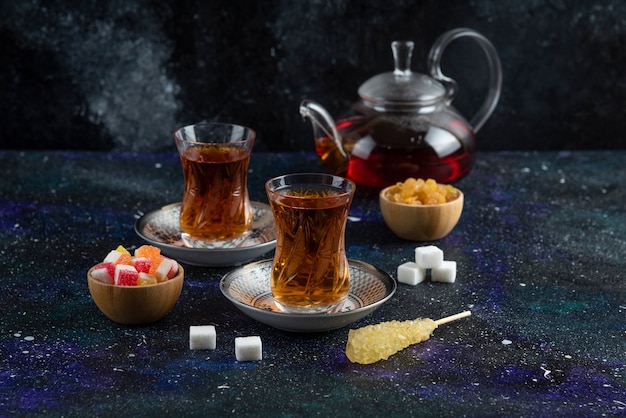 Fragrant tea with candies on blue surface