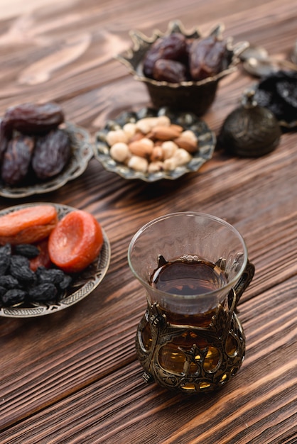 Free photo fragrant turkish tea with dried fruits; nuts and dates on textured wooden desk