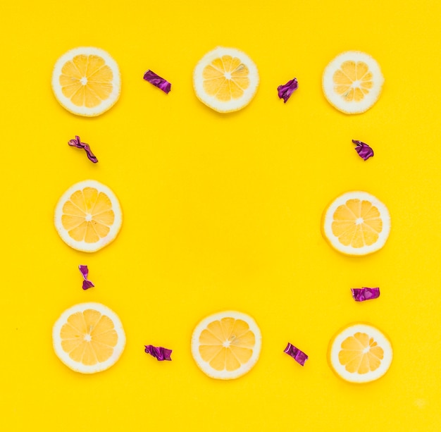 Free photo frame made with sliced lemons and chopped purple cabbage on yellow background