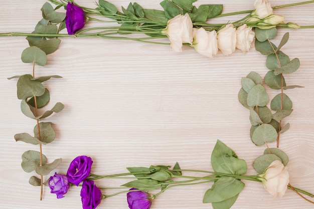 Frame made with the white and purple eustoma flowers on wooden backdrop