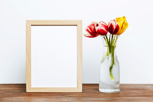 Free Photo frame near vase with flowers