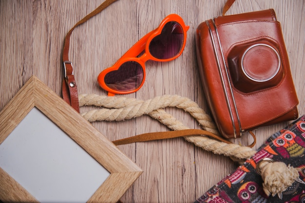 Frame, sunglasses and camera on wooden surface