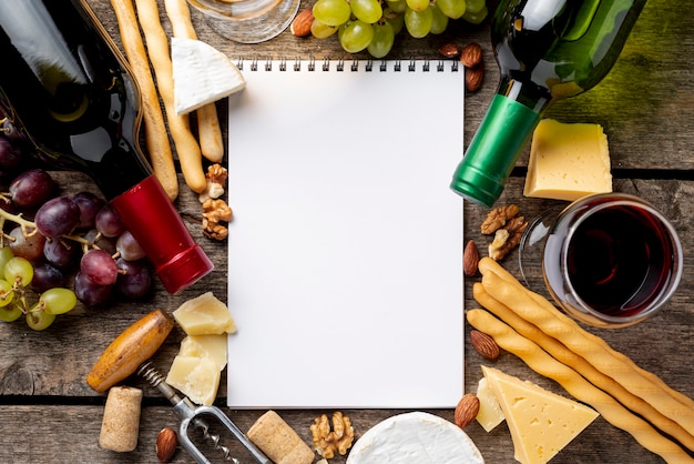 Frame of wine bottles and snack beside notebook