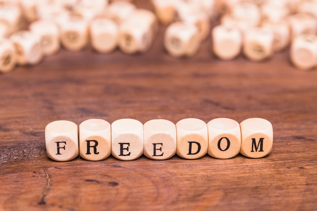 Free photo freedom word written on wooden dices over desk