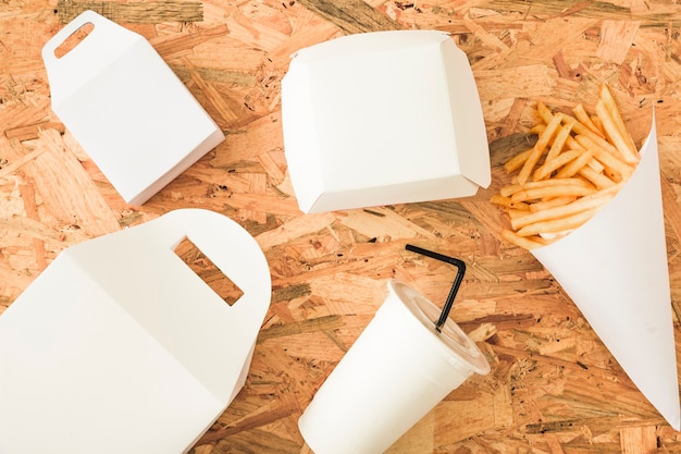 Free photo french fries; disposal cup and packages on wooden background