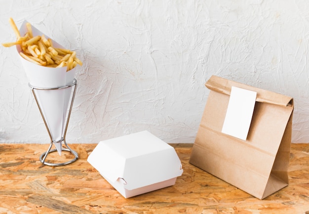 Free photo french fries and food parcel mock up on wooden table top