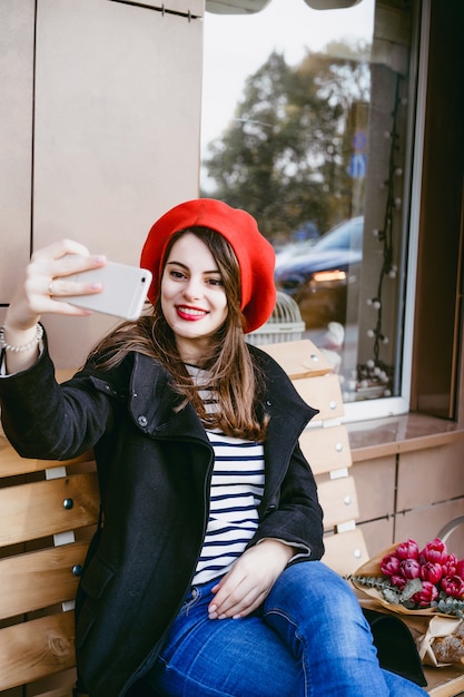 Free Photo french woman in a red beret on a street bench