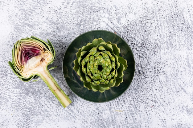 Fresh artichokes with slice top view on a light gray 