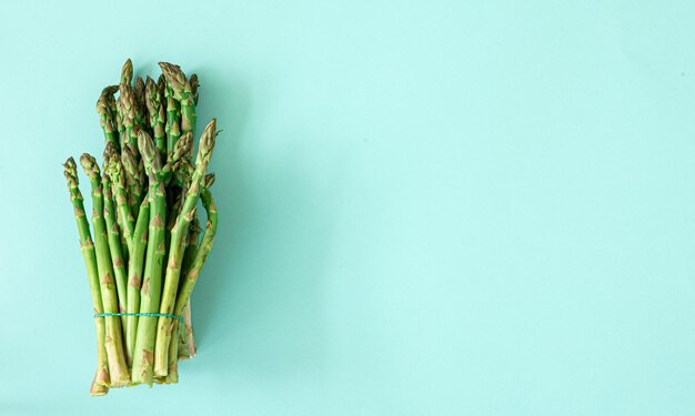 Fresh asparagus plant on blue background flat lay