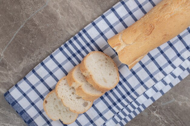 Fresh baguette slices on blue tablecloth. High quality photo