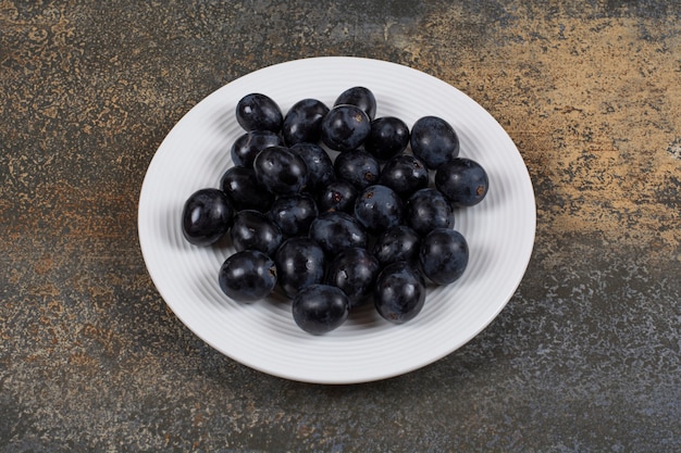 Free photo fresh black grapes on white plate.