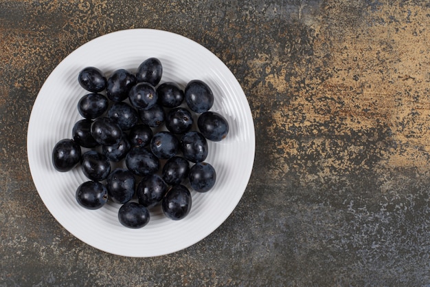 Fresh black grapes on white plate.