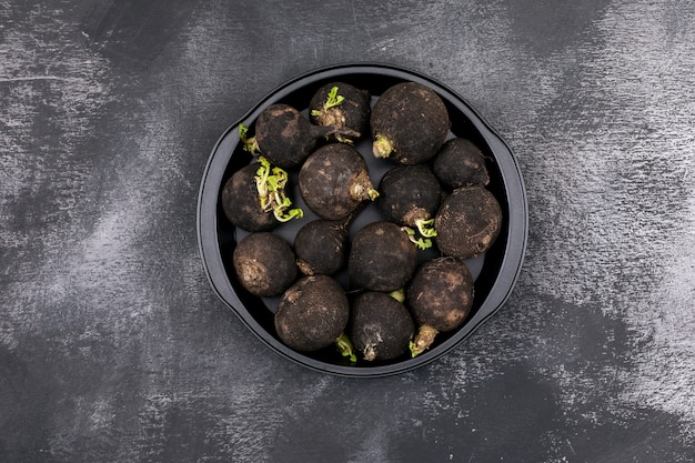 Fresh black radishes in the black pan