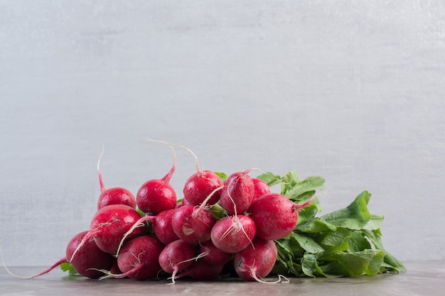 Fresh bundle of red turnips on marble.