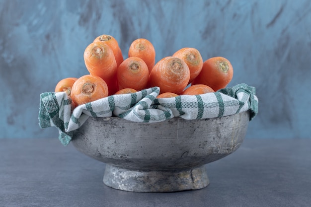 Fresh carrots on towel in the bowl , on the marble surface.