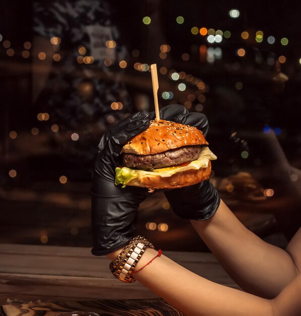 Fresh cheeseburger in black gloves