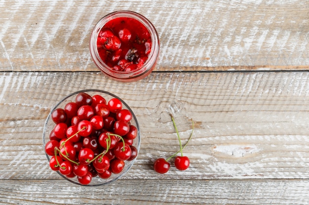 Fresh cherries in a vase with cherry jam on a wooden