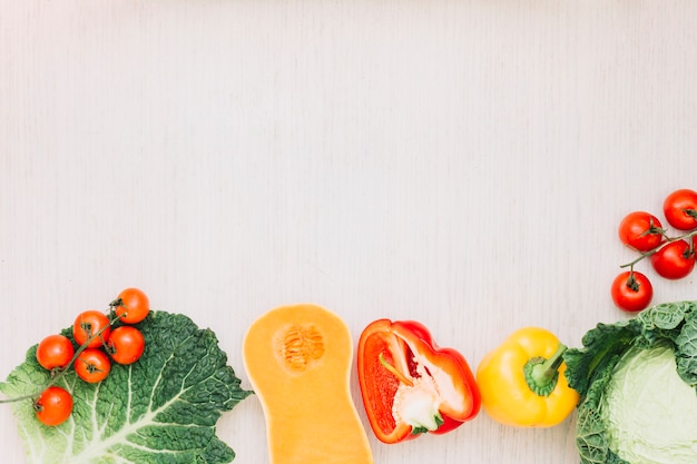 Fresh cherry tomatoes; cabbage; bell pepper and butternut squash on wooden surface