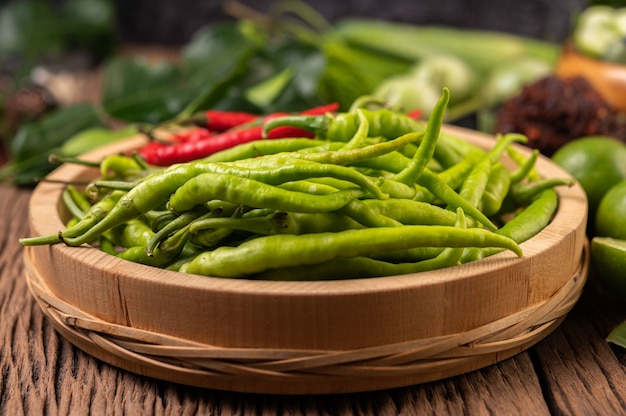 Fresh chili on a wooden tray with lemon and kaffir lime leaves.