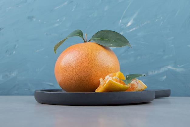 Fresh clementine and segments on black cutting board