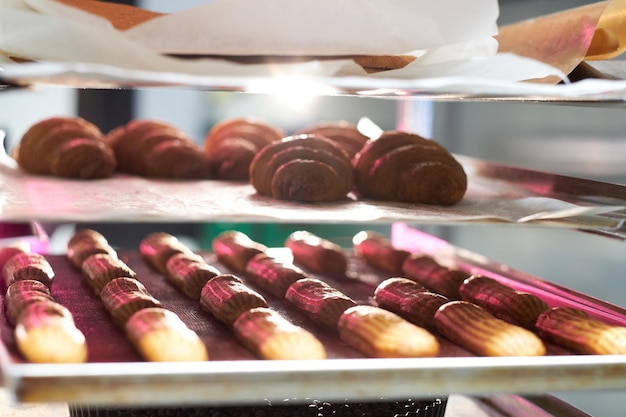 Fresh cookies with chocolate are ready to be removed from the oven at bakery shop.