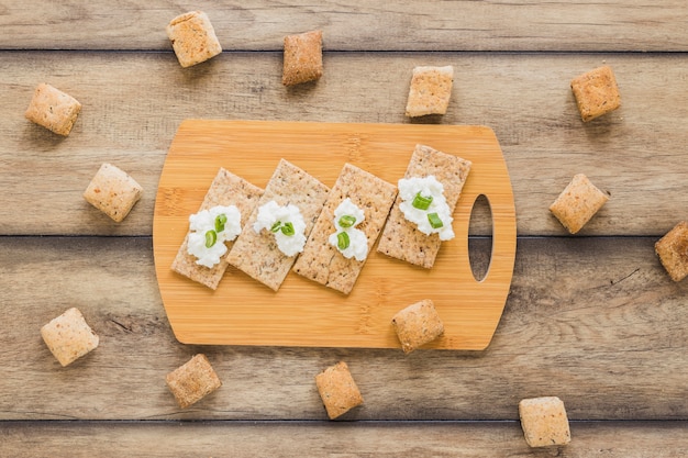 Fresh cream cheese on crisp bread over the chopping board on desk