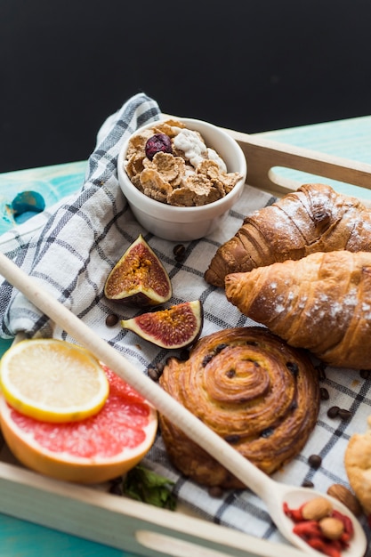 Fresh croissant; sweet pastry; cornflake; fig and citrus fruits served for breakfast in tray