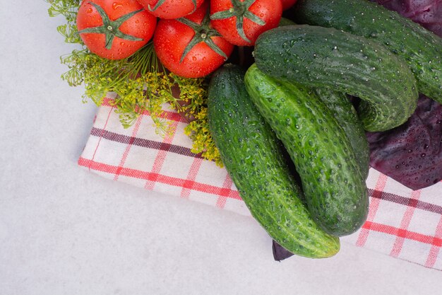 Free Photo fresh cucumbers, tomatoes and basil on tablecloth