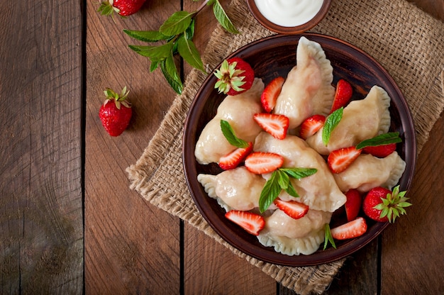 Fresh dumplings with strawberries and sour cream