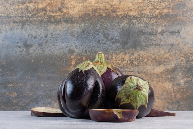 Fresh eggplants with water drops on stone surface. High quality photo