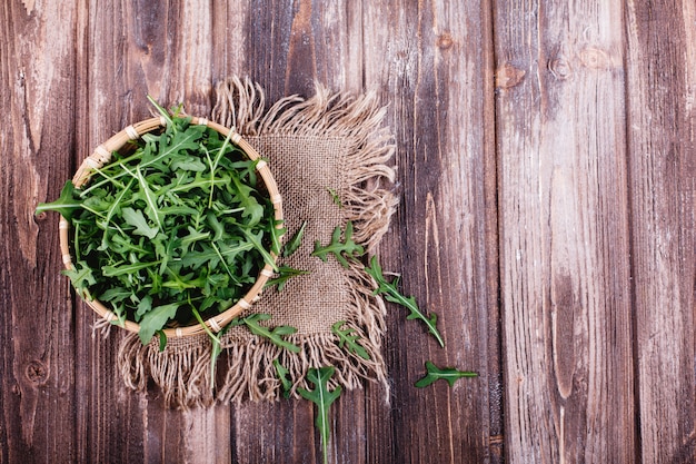 Fresh food, healthy life. Green arugula served in the bowl on rustic background 