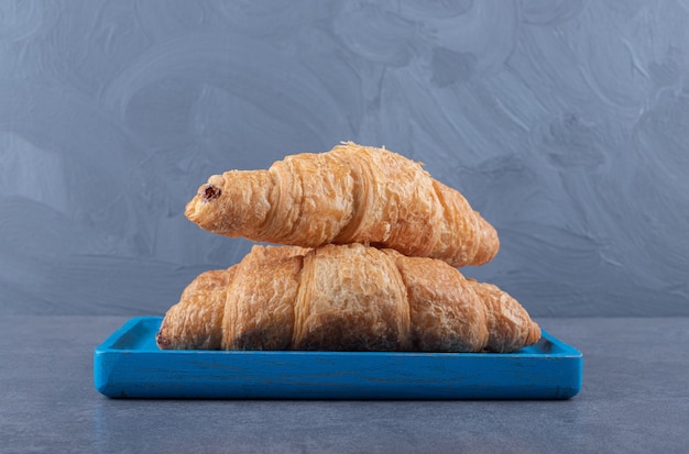 Free photo fresh french croissants with a golden crust. on blue wooden board.