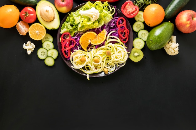 Free photo fresh fruits and chopped vegetables against black backdrop