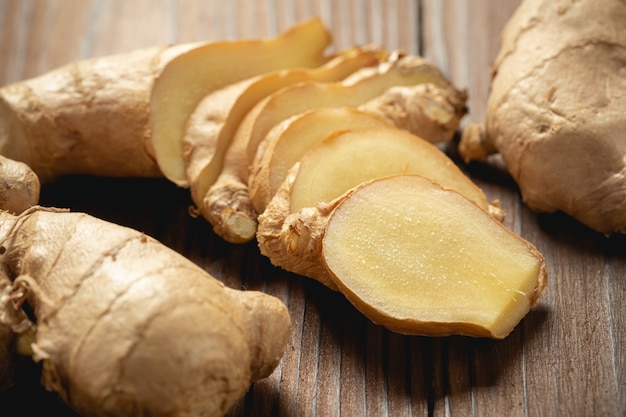 Fresh ginger root and sliced on wooden table.