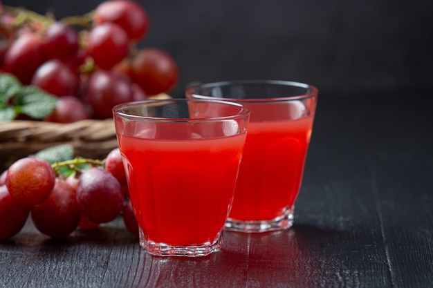 Fresh grape juice on the dark wooden surface.