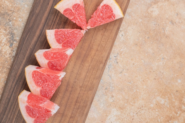 Free photo fresh grapefruit slices on wooden board.