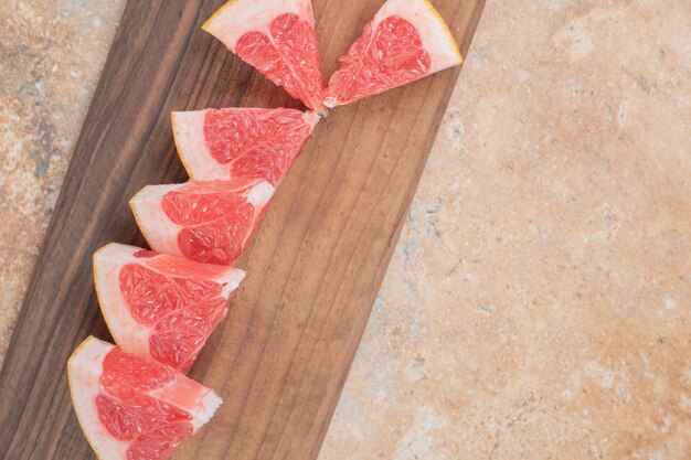 Fresh grapefruit slices on wooden board. 