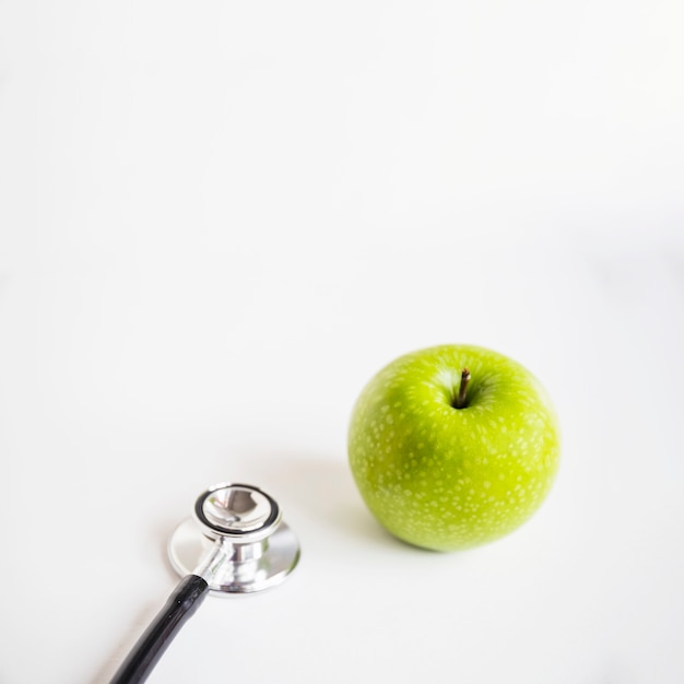 Free photo fresh green apple and stethoscope on white background