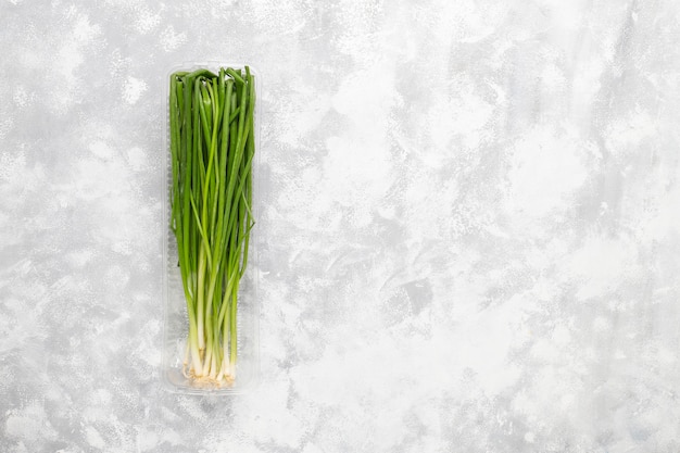 Free photo fresh green onions in plastic box on grey concrete