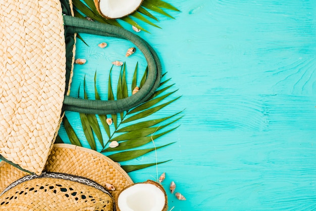 Fresh green plant leaves near handbag and hat with coconut