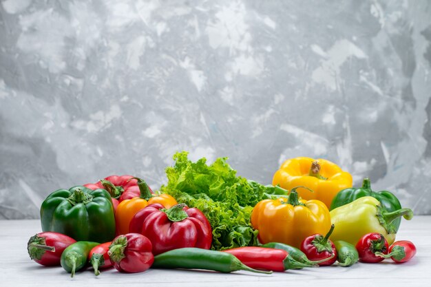 fresh green salad along with colored bell peppers and spicy peppers composition on light desk