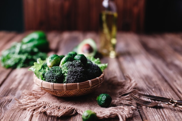 Fresh and healthy food. Wooden bowl with broccoli, brussel sprouts, olive oil, green pepper