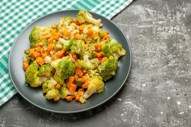 Fresh and healthy vegetable salad on green stripped towel on gray table