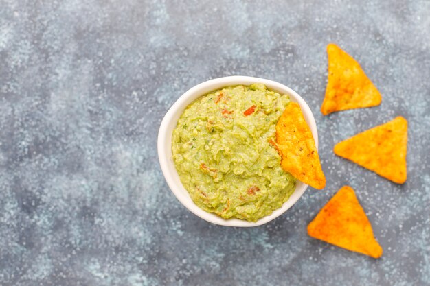 Fresh homemade hot guacamole sauce with nachos, top view