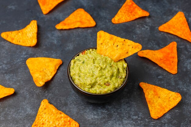 Fresh homemade hot guacamole sauce with nachos, top view