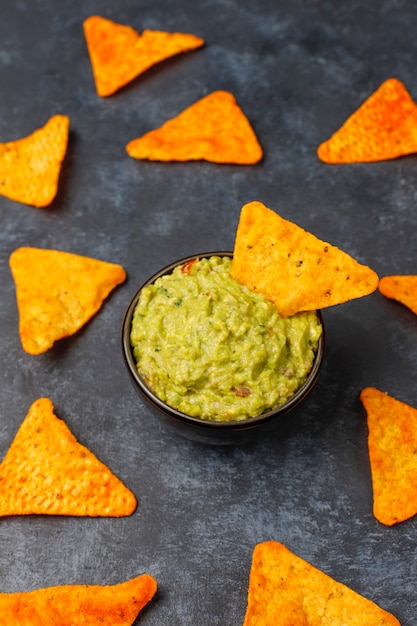 Fresh homemade hot guacamole sauce with nachos, top view