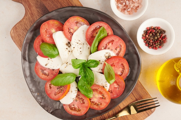 Fresh Italian salad antipasto called caprese with buffalo mozzarella, sliced tomatoes and basil with olive oil. Ingredients for vegetarian caprese salad. Italian food. top view. Rustic style.